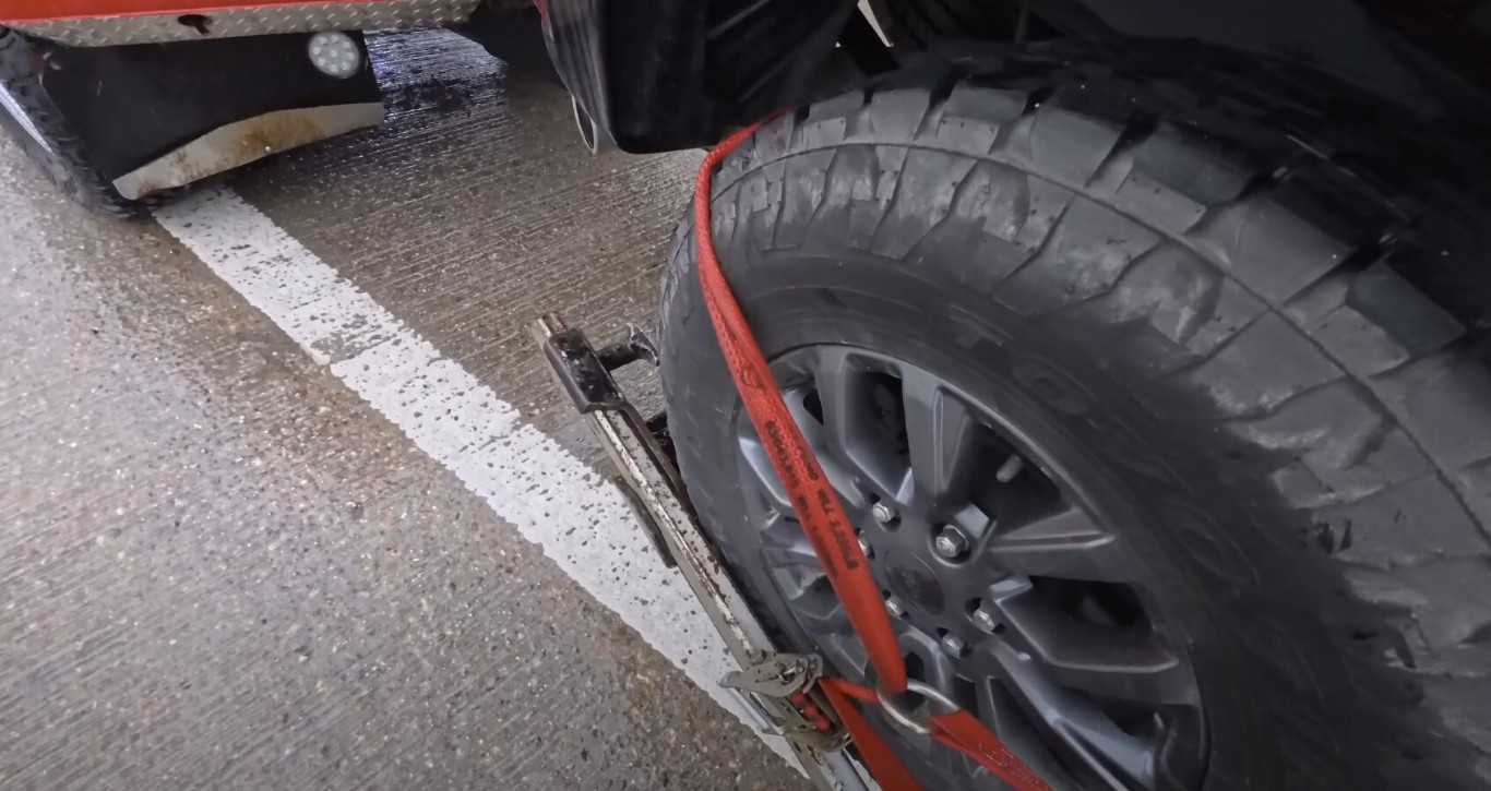 Professional towing technician securing vehicle on flatbed